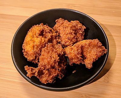 Image of fried pakoras with chickpeas in a black bowl.