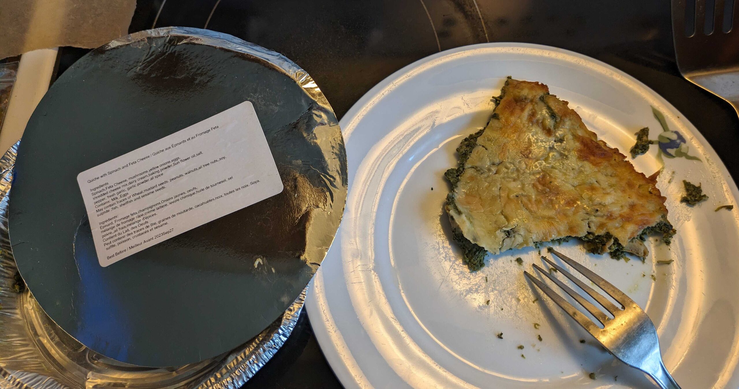 Bad spinach quiche on a white plate with a fork and a pie plate.