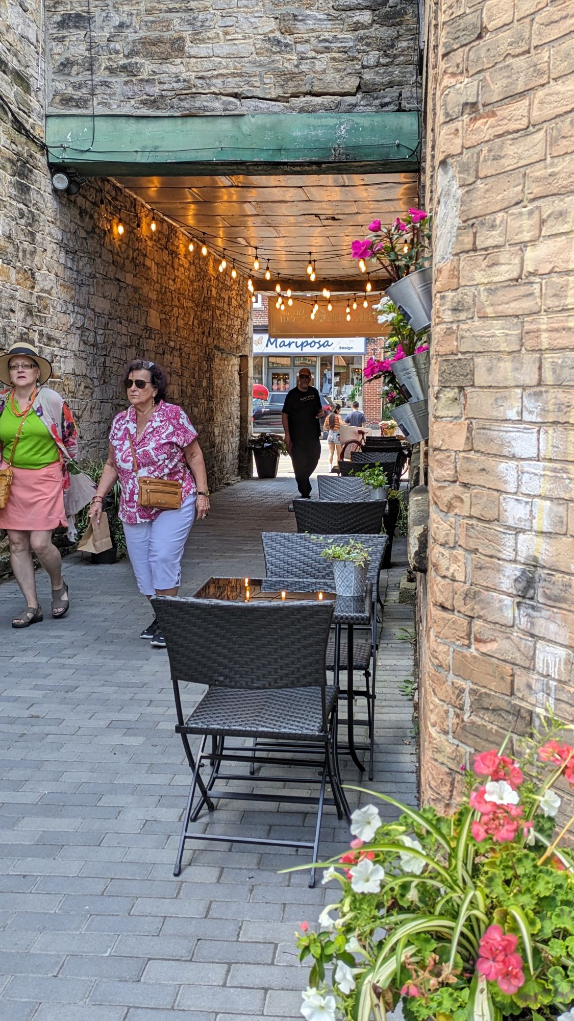 Brick wall, flowers and patio tables outside of Stella Luna Gelato in Perth, ON.